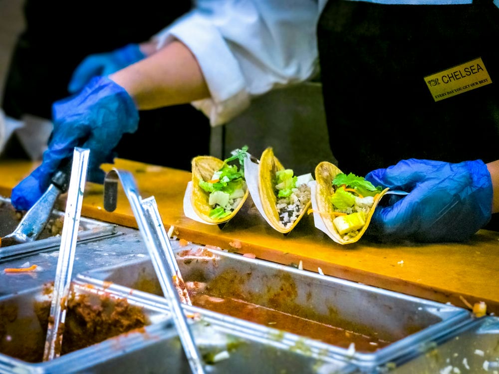 Restaurant staff using digital tablet for food safety checks in commercial kitchen
